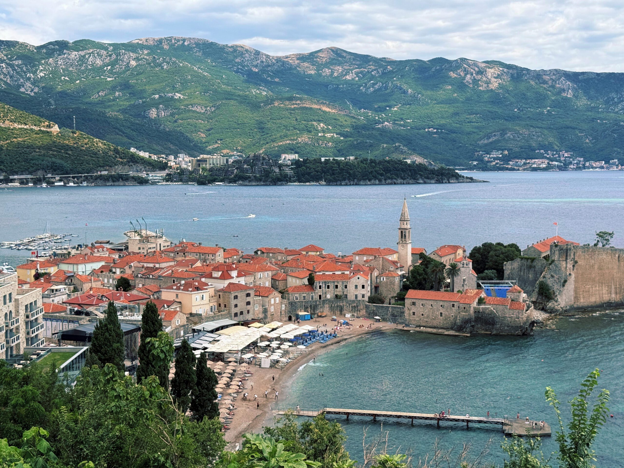 Landscape of Budva, Montenegro with clear waters, historic fortress towns, and limestone mountains in the background
