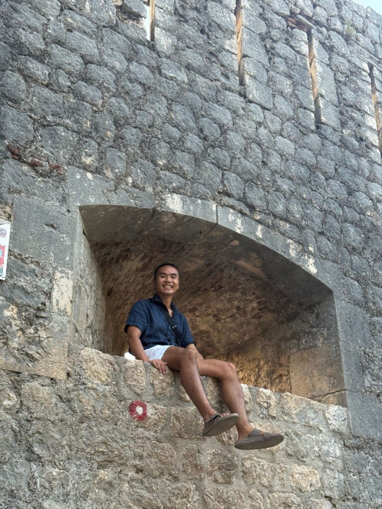 Person sitting on small opening in the fortress wall