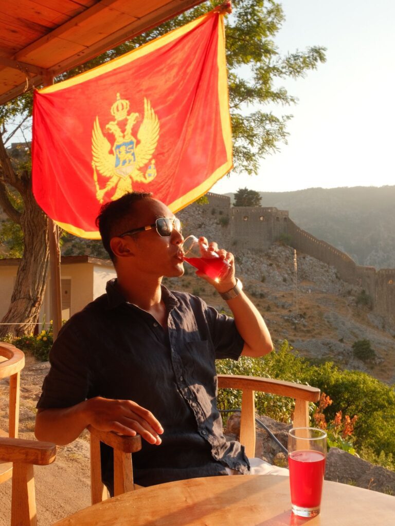 Sunset drink with Kotor Fortress and Montenegro flag