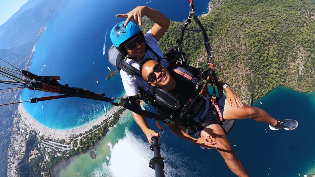 Tandem paragliding over Ölüdeniz Blue Lagoon in Turkey with turquoise coastline and mountains below