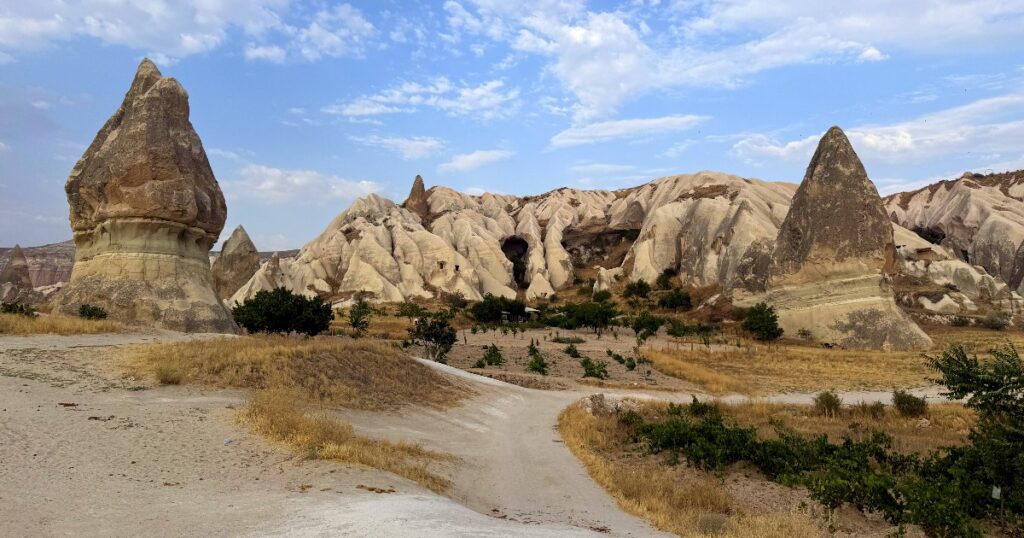 Distinctive fairy chimney rock formations dotting the Cappadocia landscape under blue sky.