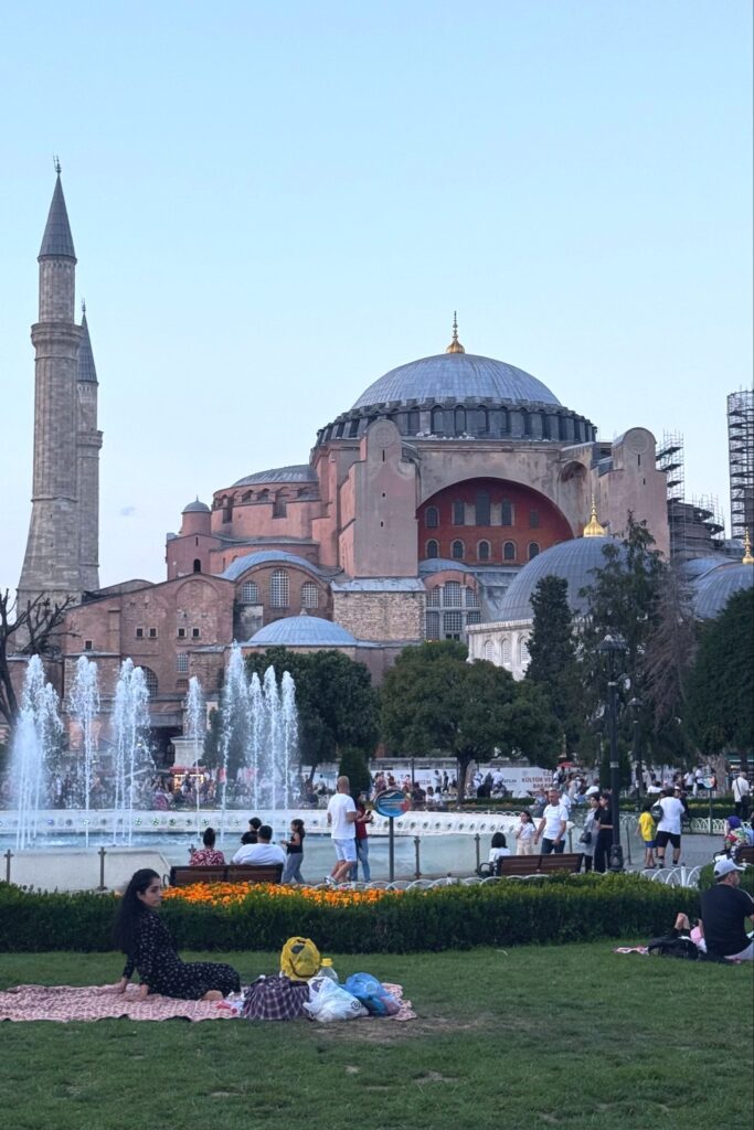 Hagia Sophia's grand dome and minaret rise above fountains in Istanbul's historic sultanahmet square.