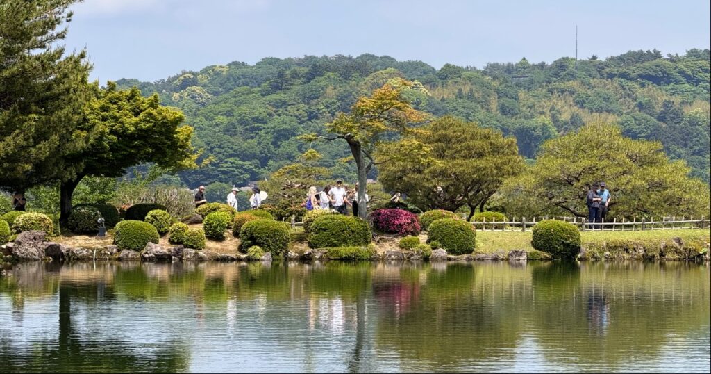 Lush trees reflected in calm water at Kenrokuen Garden in Kanazawa.