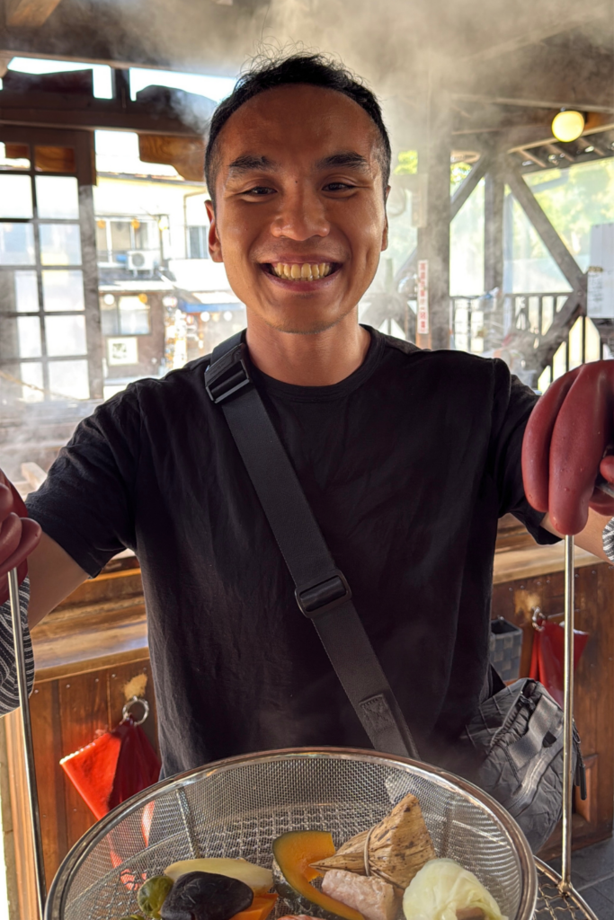 Traveler holding a basket of hell-steamed food at a jigoku-mushi restaurant in Beppu.