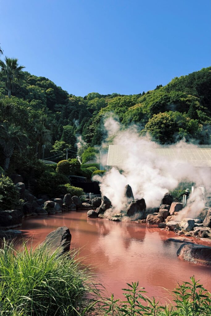 Red pond with geothermal steam in Beppu's Jigoku Meguri.