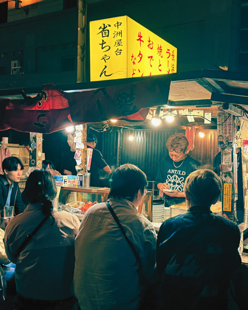 Customers gathered at illuminated yatai food stalls in Fukuoka's vibrant nighttime street food scene.