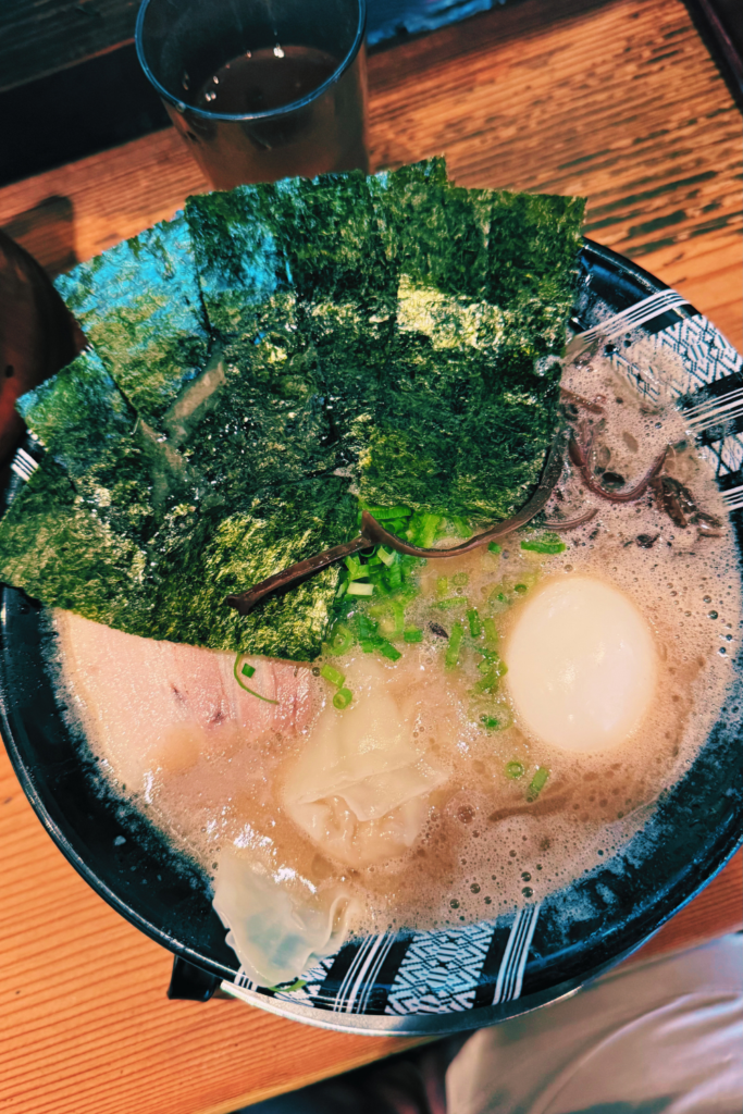Bowl of creamy Hakata tonkotsu ramen topped with nori seaweed and a soft-boiled egg.