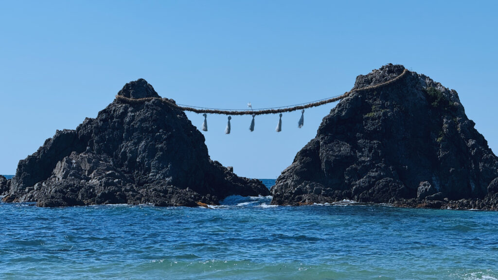 Two rocky peaks connected by a rope bridge over blue ocean waters at Itoshima Island.