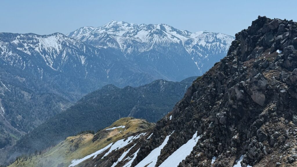 Snow-capped Northern Alps peaks viewed from the rocky ridge of Mount Yakedake on a clear day