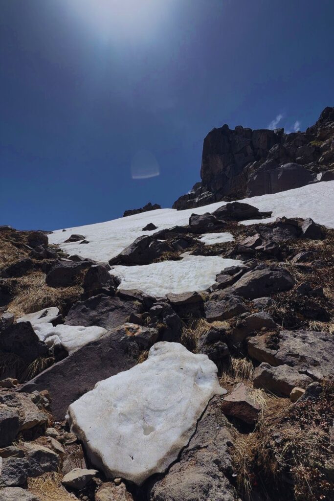 Rocky summit terrain with snow fields and blue sky on Mount Yakedake in the Northern Alps