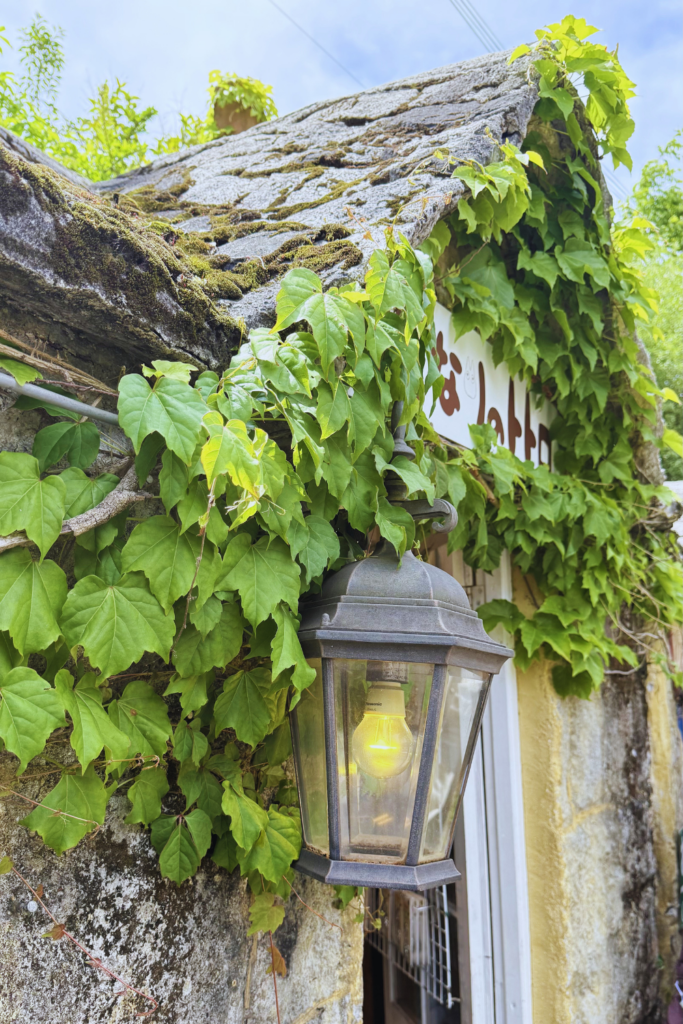 Ivy-covered stone building with a vintage brass lantern at Yufuin Floral Village.