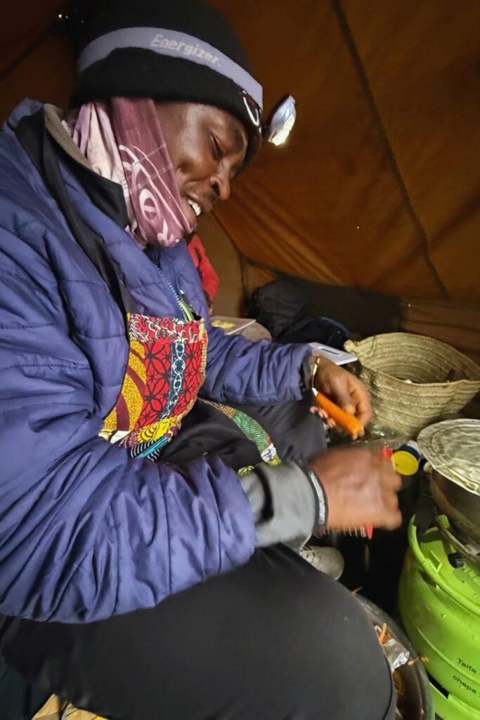 Chef Peter preparing dinner by headlamp in the cook tent on Kilimanjaro