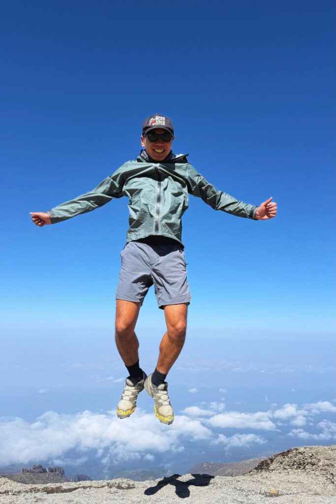 Hiker jumping for joy above the clouds on the way up Kilimanjaro