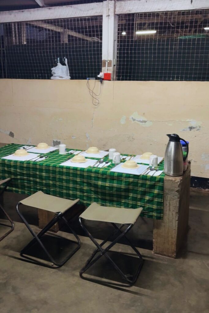 A camp dining table set with plates, mugs, and a thermos for breakfast