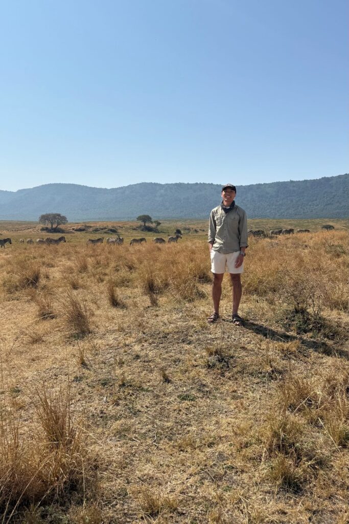 A man standing near a group of zebras in Ngorongoro Crater