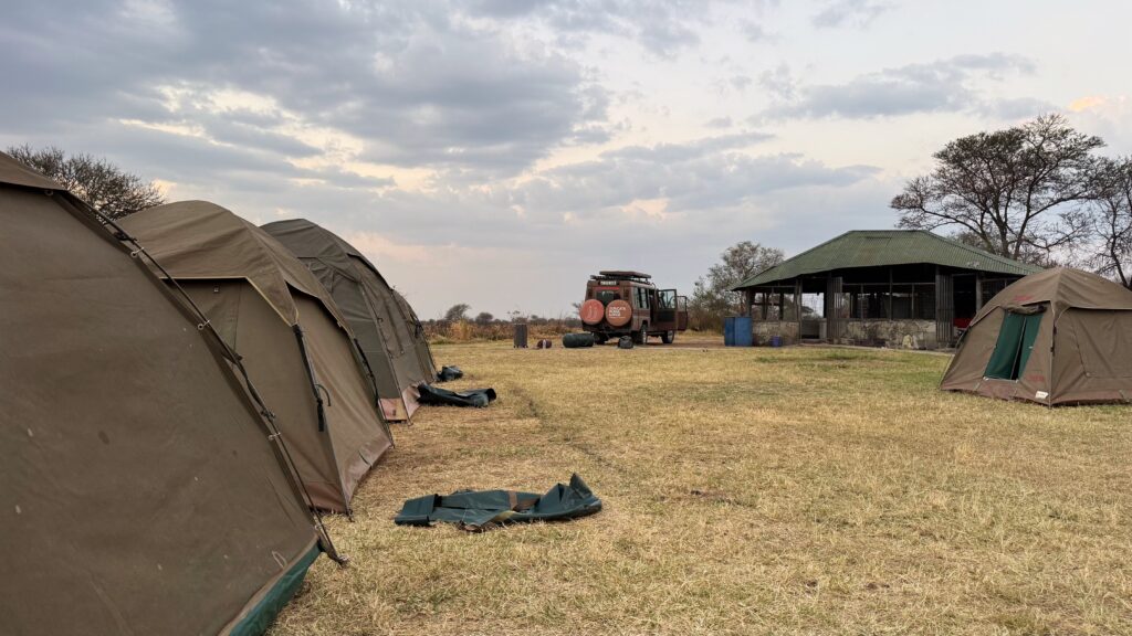 A wide view of a tent campsite with hot air balloons floating in the distant sky