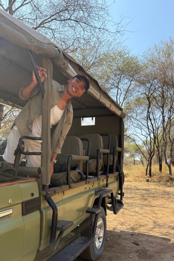 A man smiling in an open-sided safari vehicle