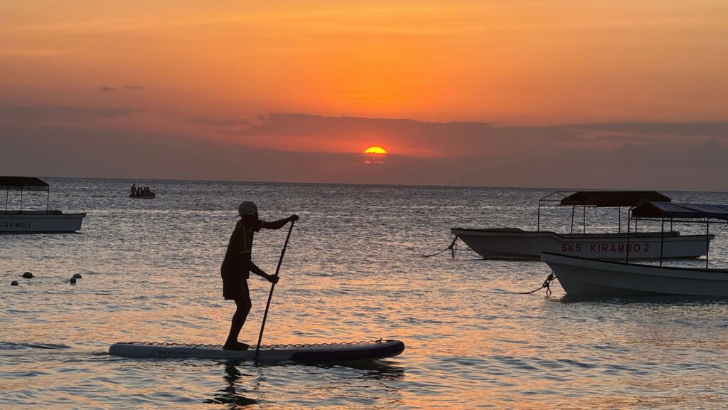 Paddleboarder silhouetted against a Zanzibar sunset