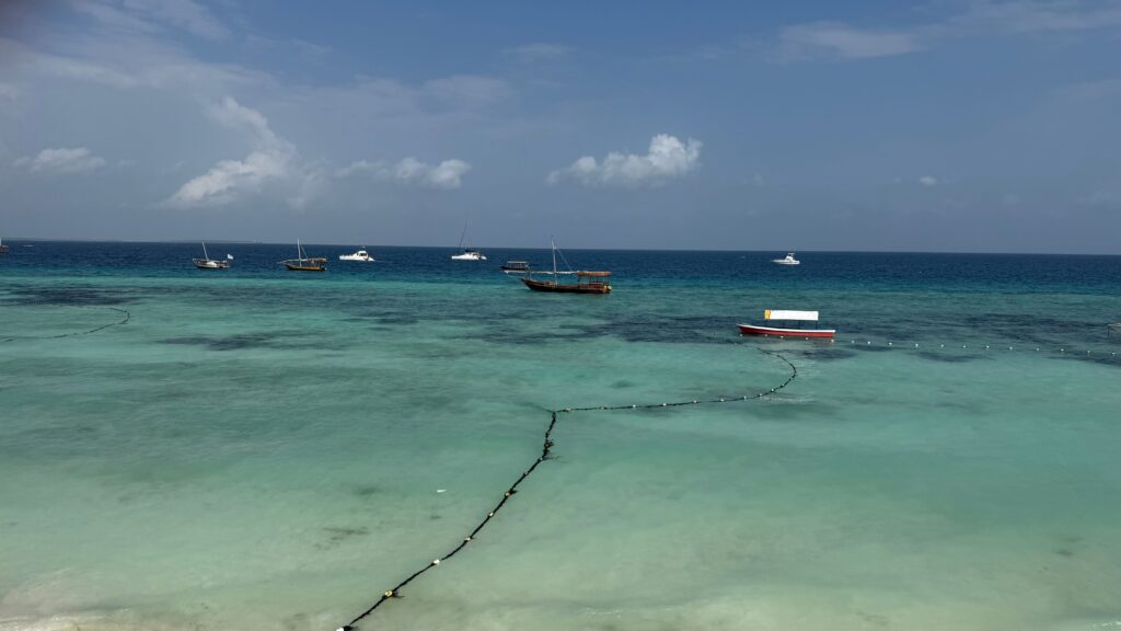 Boats floating on turquoise water off the coast of Zanzibar