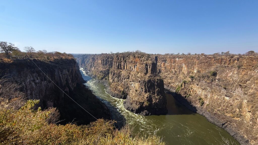 The deep Batoka Gorge near Victoria Falls, with the green Zambezi River winding between steep cliffs and cables stretched across the top