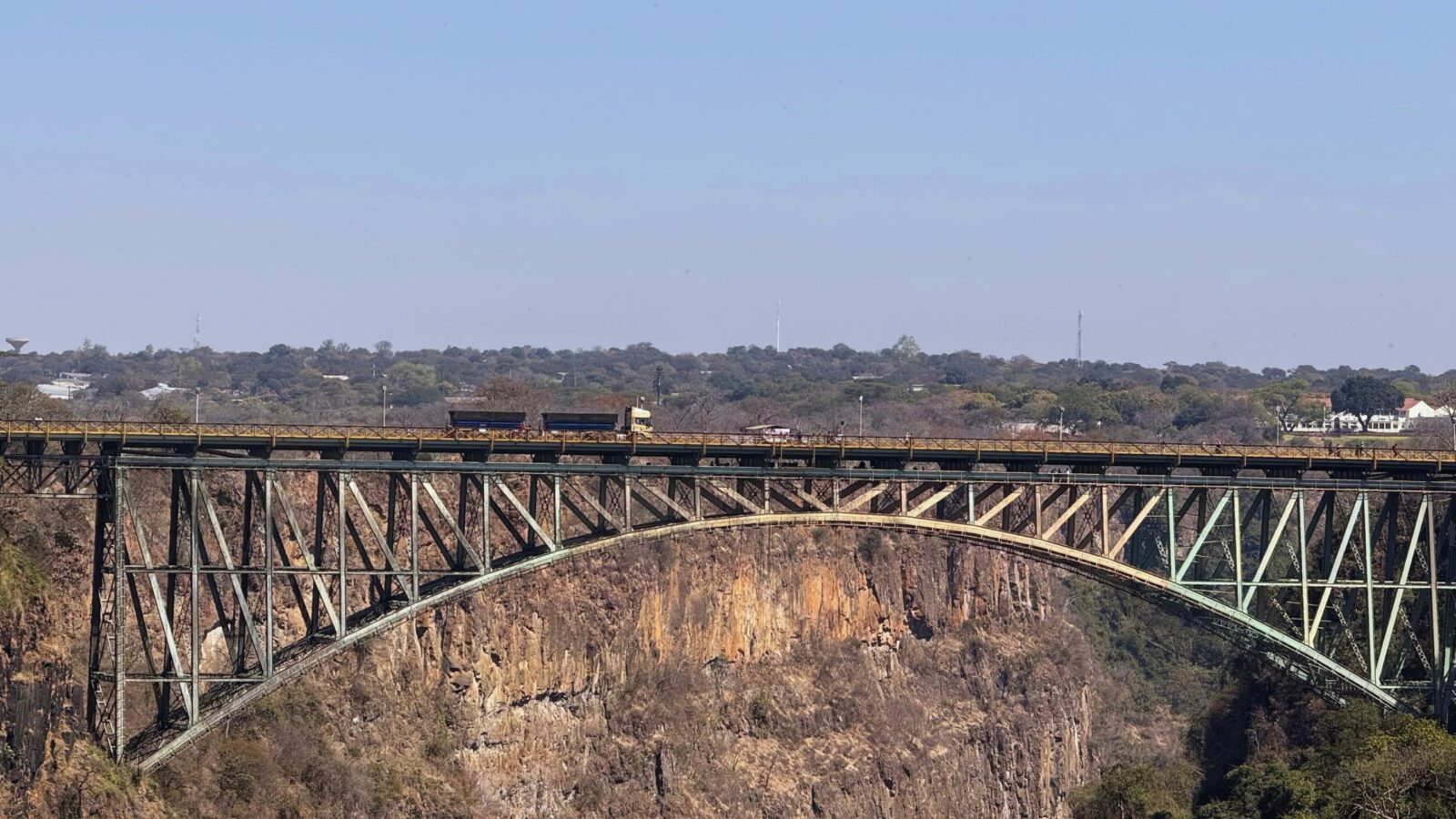 Victoria Falls Bridge, a steel arch bridge over the Zambezi gorge, with a truck crossing between Zambia and Zimbabwe