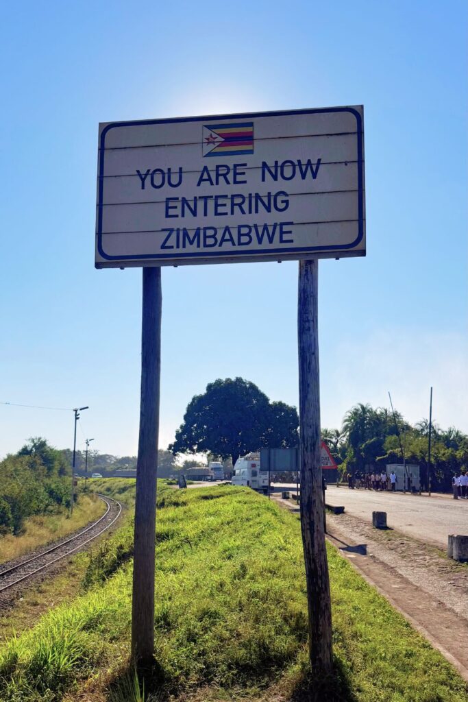 You Are Now Entering Zimbabwe sign with the Zimbabwe flag near the Victoria Falls border